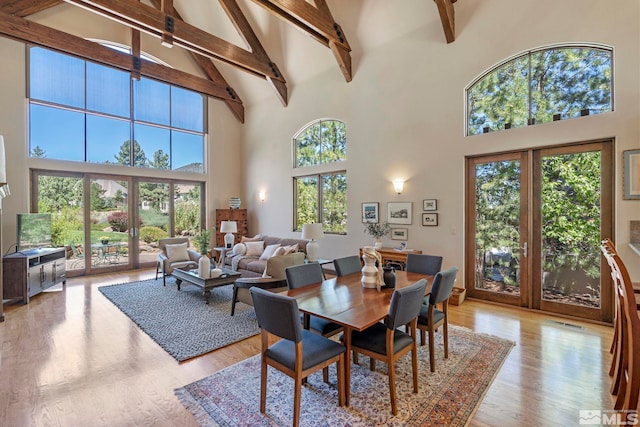 dining room with light hardwood / wood-style floors, beam ceiling, high vaulted ceiling, and french doors