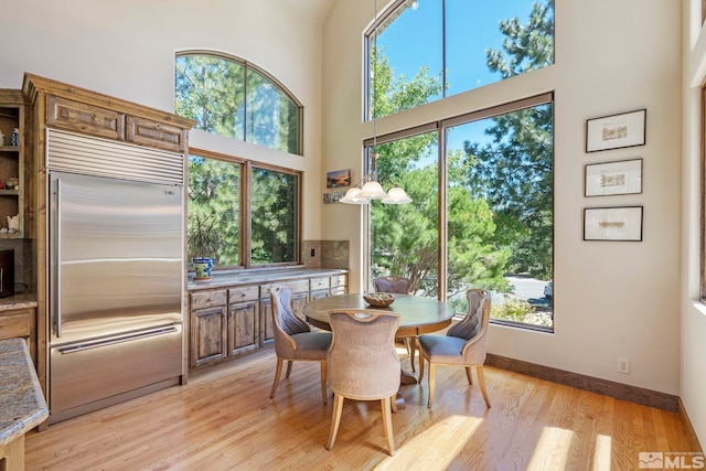 dining space featuring a towering ceiling and light hardwood / wood-style flooring