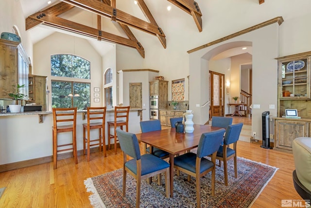 dining room featuring light wood-type flooring, beam ceiling, and high vaulted ceiling