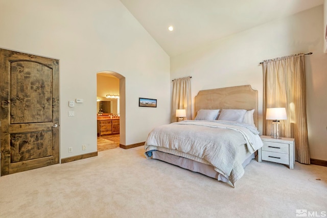 bedroom featuring high vaulted ceiling, ensuite bathroom, and light carpet