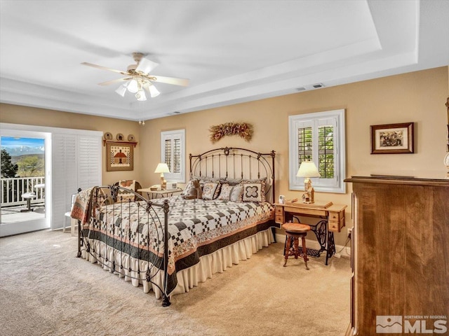 bedroom featuring access to exterior, a raised ceiling, visible vents, light carpet, and ceiling fan