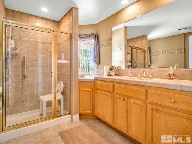 bathroom with a shower stall, vanity, visible vents, and tile patterned floors