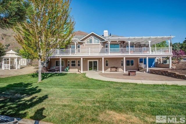 rear view of house with a patio, a fire pit, a yard, stucco siding, and a pergola