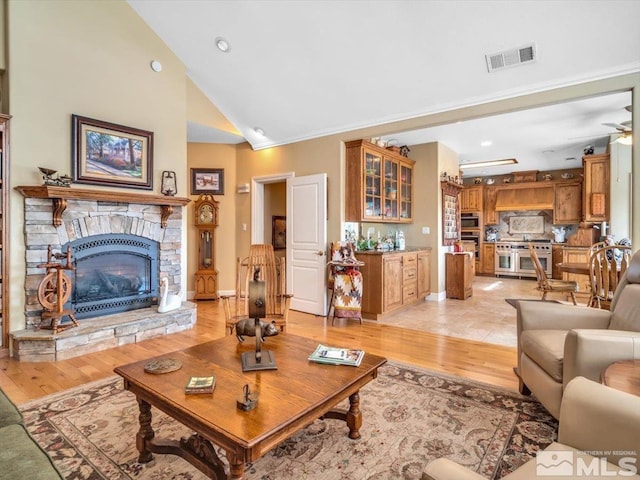 living area with light wood-style flooring, a fireplace, visible vents, and a ceiling fan