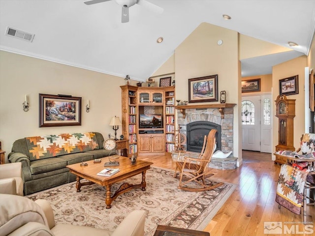 living area with light wood-style floors, visible vents, a fireplace, and a ceiling fan