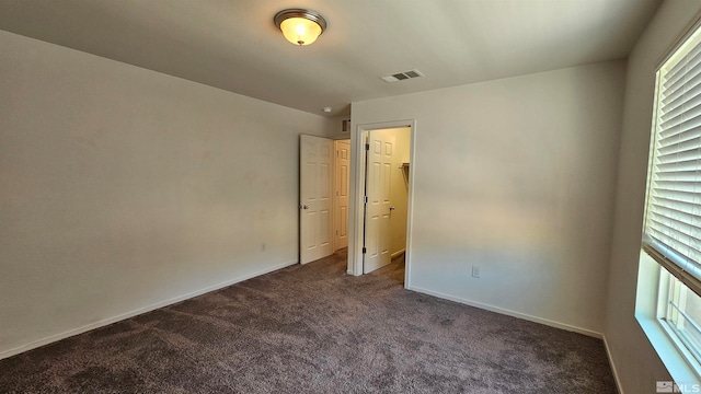 unfurnished bedroom with dark carpet