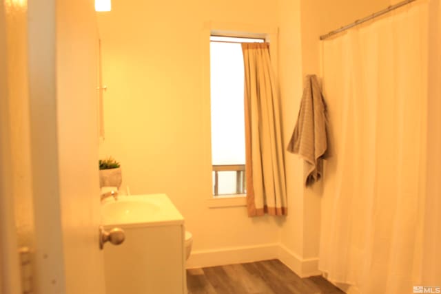 full bath featuring toilet, baseboards, wood finished floors, and vanity