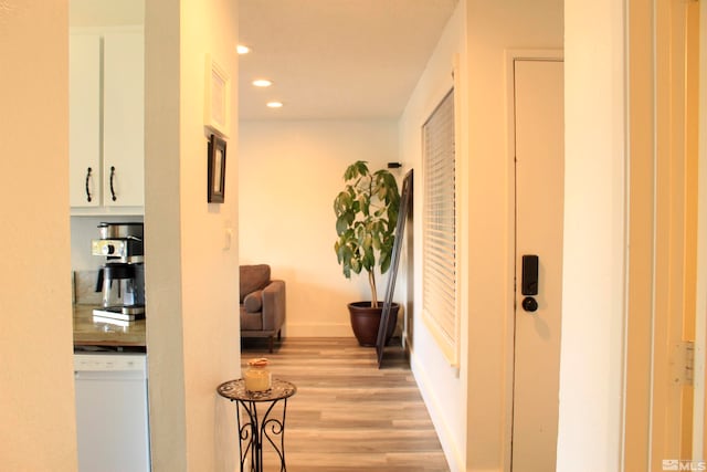 hall with baseboards, light wood finished floors, and recessed lighting