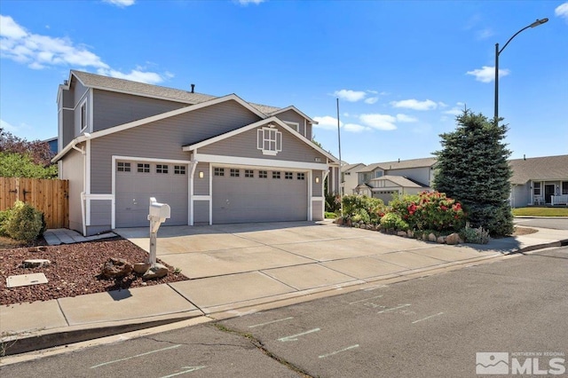 view of front of home featuring driveway, an attached garage, and fence