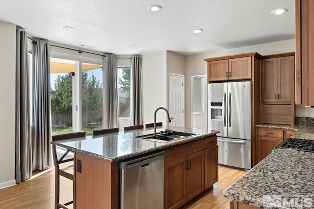 kitchen featuring appliances with stainless steel finishes, an island with sink, light hardwood / wood-style floors, and sink