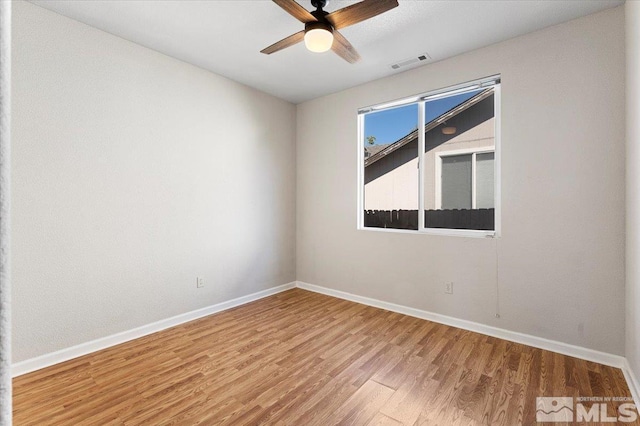 spare room featuring a ceiling fan, wood finished floors, visible vents, and baseboards