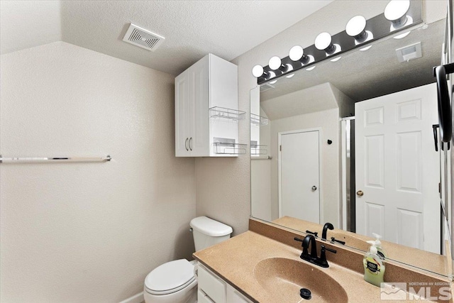 bathroom featuring visible vents, vaulted ceiling, vanity, and toilet