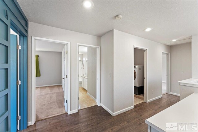 interior space featuring washer / clothes dryer, a textured ceiling, and dark colored carpet