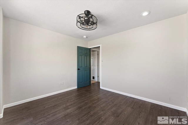 empty room featuring baseboards and dark wood finished floors