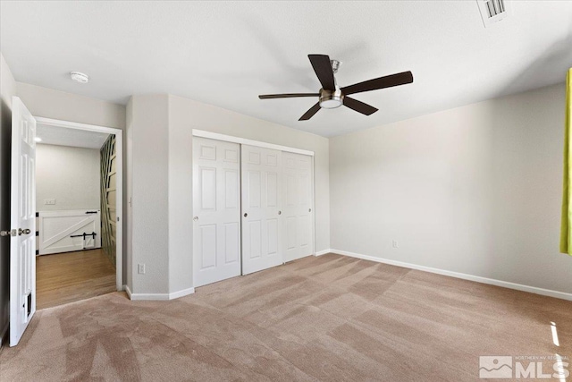 unfurnished bedroom with ceiling fan, light colored carpet, visible vents, baseboards, and a closet