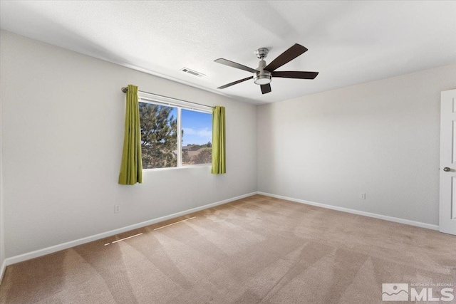 unfurnished room with carpet floors, visible vents, baseboards, and a ceiling fan