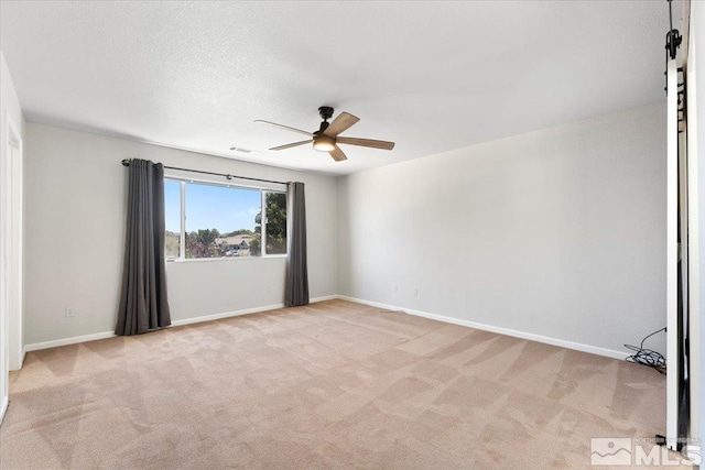 unfurnished room featuring light carpet, a textured ceiling, a ceiling fan, and baseboards