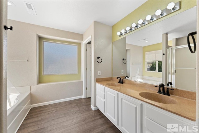 bathroom featuring dual vanity, hardwood / wood-style flooring, and a bath