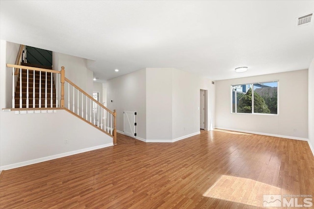 unfurnished room with visible vents, stairway, baseboards, and wood finished floors