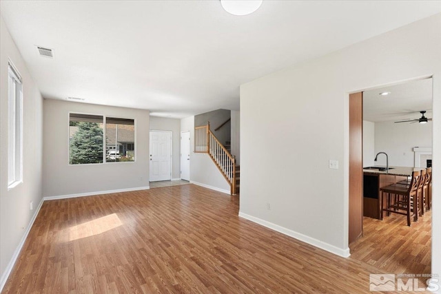 living room featuring light hardwood / wood-style flooring, sink, and ceiling fan