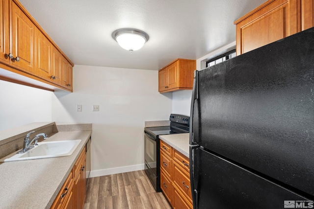 kitchen with black appliances, sink, and light hardwood / wood-style floors