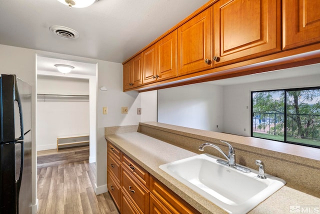 kitchen featuring fridge, sink, and light hardwood / wood-style floors