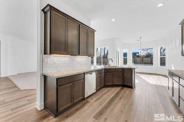 kitchen with hanging light fixtures, tasteful backsplash, dark brown cabinetry, light stone countertops, and stainless steel dishwasher