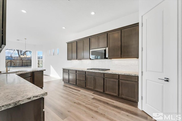 kitchen featuring stainless steel appliances, decorative light fixtures, sink, and dark brown cabinets