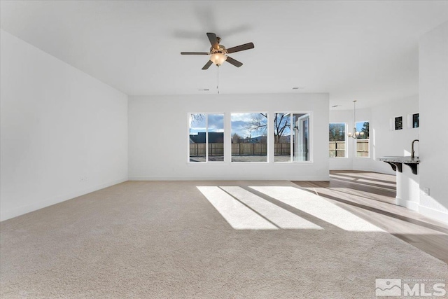 unfurnished living room with light colored carpet and ceiling fan