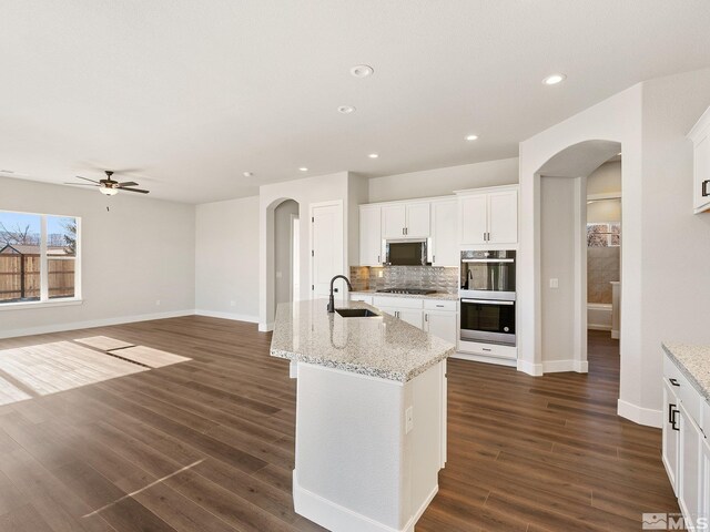 kitchen with hardwood / wood-style floors, decorative backsplash, gray cabinets, dark stone countertops, and stainless steel appliances