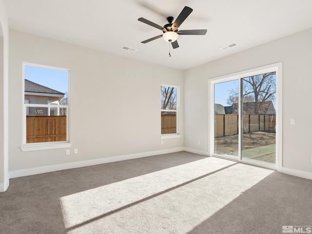 carpeted empty room featuring baseboards, visible vents, and a ceiling fan