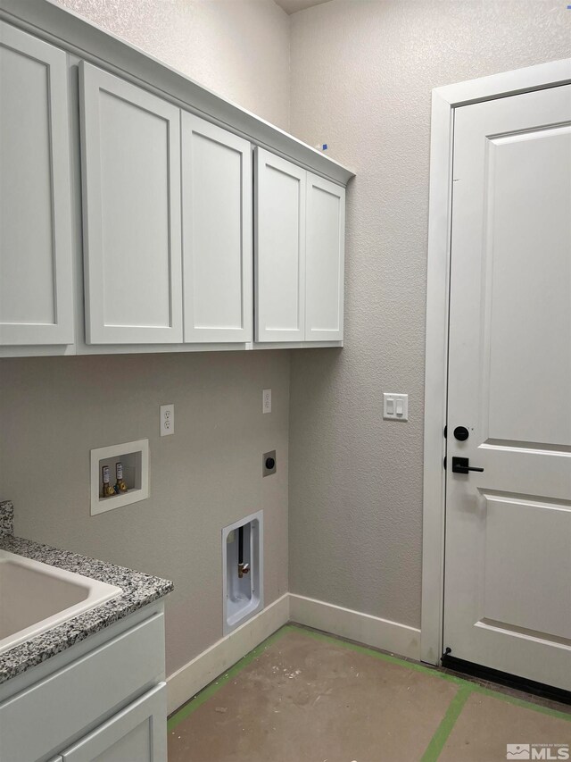 laundry area with hookup for a washing machine, cabinet space, a textured wall, electric dryer hookup, and baseboards