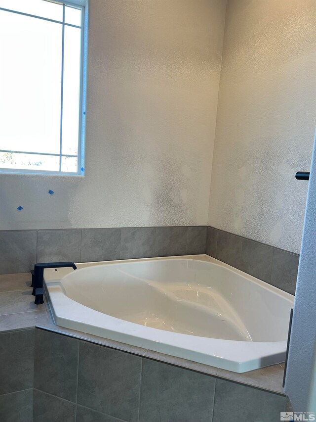 full bathroom with a textured wall and a bath