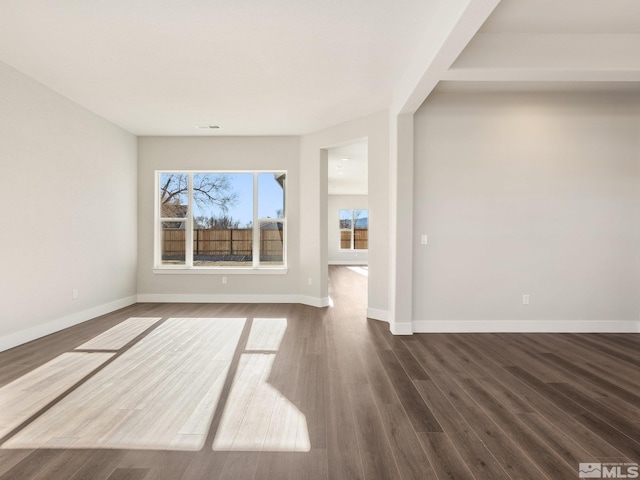 spare room with dark wood-style floors, visible vents, and baseboards