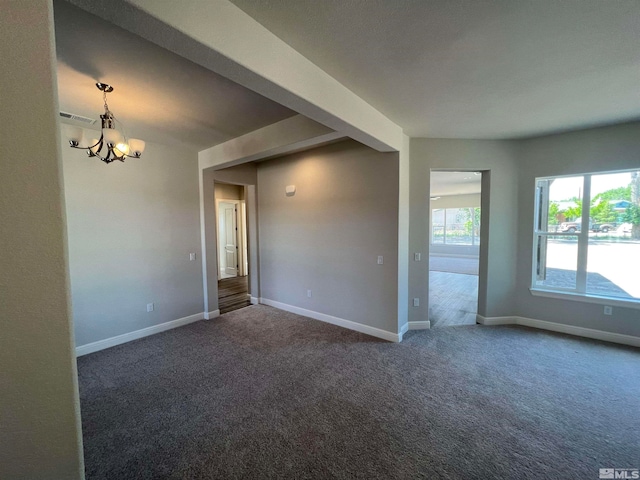 carpeted empty room featuring a notable chandelier