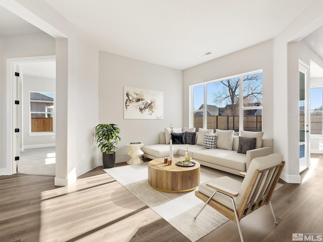 living room with visible vents, baseboards, and wood finished floors