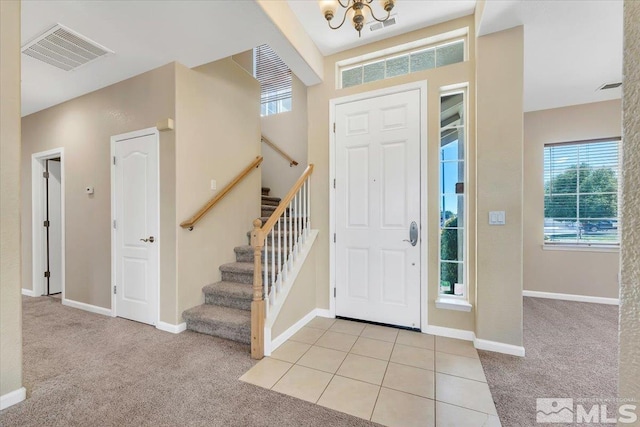 foyer with stairway, baseboards, visible vents, and light colored carpet