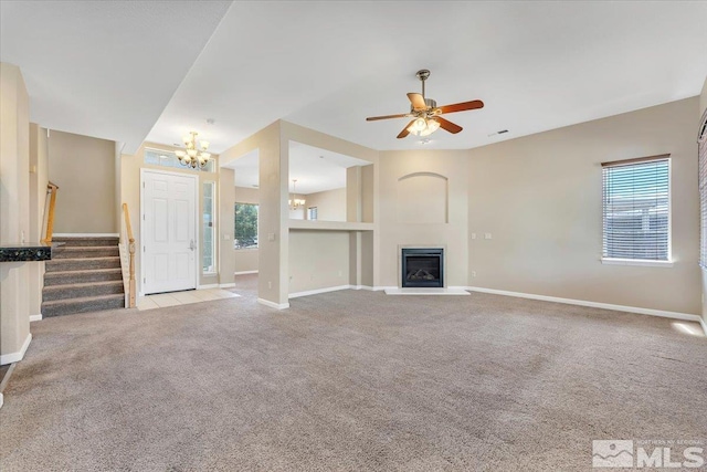 unfurnished living room featuring light colored carpet, visible vents, a glass covered fireplace, baseboards, and stairs