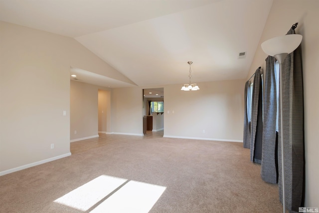 carpeted spare room with lofted ceiling and a chandelier