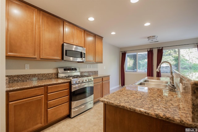 kitchen featuring sink, stainless steel appliances, light tile patterned floors, and stone countertops