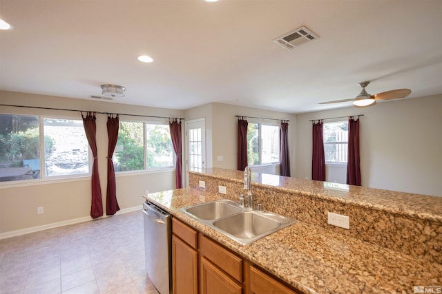 kitchen with light tile patterned floors, light stone countertops, ceiling fan, sink, and stainless steel dishwasher