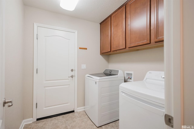 laundry room with light tile patterned flooring, washing machine and dryer, and cabinets