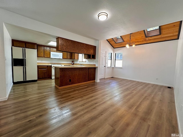 kitchen with hanging light fixtures, an inviting chandelier, dark hardwood / wood-style flooring, lofted ceiling with skylight, and white appliances