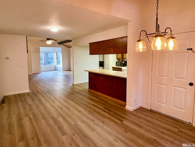 kitchen with pendant lighting, ceiling fan with notable chandelier, dark hardwood / wood-style flooring, and kitchen peninsula