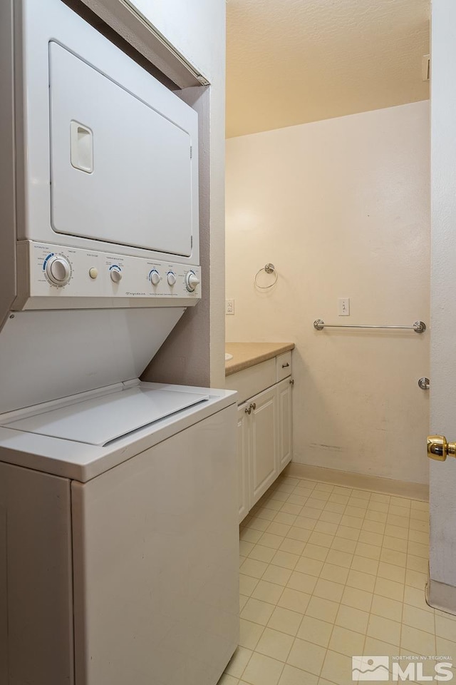 laundry room with stacked washer / drying machine and light tile patterned floors