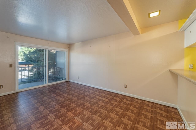 unfurnished room with beamed ceiling, a textured ceiling, and dark parquet floors