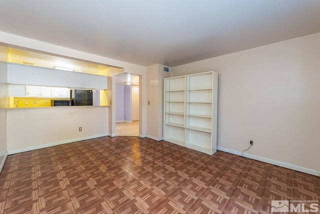 spare room featuring sink and dark parquet floors