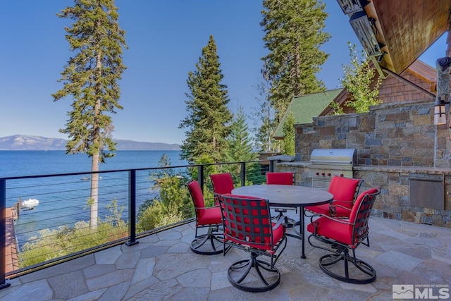 view of patio with exterior kitchen, a water and mountain view, and area for grilling