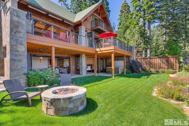 rear view of house featuring a balcony, an outdoor fire pit, a patio, and a yard