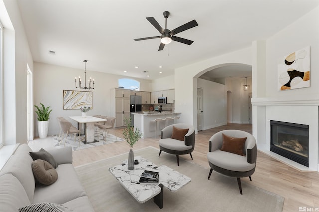 living room with light hardwood / wood-style floors and ceiling fan with notable chandelier